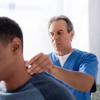 Lékař provádí diagnostické vyšetření pacienta s bolestí krku